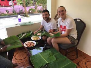 two people sitting around a table with plates of food at Lavender residency in Varkala