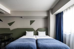 a bedroom with two beds with blue sheets and a window at Section L Kuramae - Asakusa in Tokyo