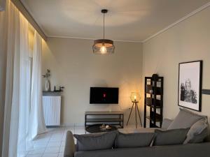 a living room with a couch and a tv at White elephant first floor apartment in Volos