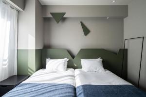 a bedroom with two beds and a green headboard at Section L Kuramae - Asakusa in Tokyo