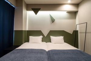 a bedroom with a bed with a green headboard at Section L Kuramae - Asakusa in Tokyo