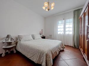 a white bedroom with a bed and a window at Casetta nel verde in Varazze