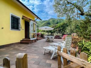 a patio with white chairs and an umbrella at Casetta nel verde in Varazze