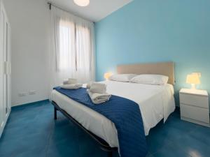 Elimi Favignana Apartments - Residence in città في فافينانا: غرفة نوم زرقاء مع سرير عليه مناشف
