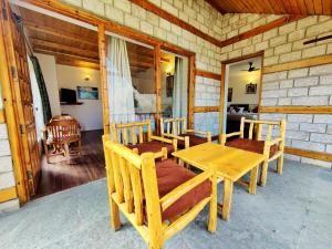 a porch of a cabin with a wooden table and chairs at Harippur Cottages and Resort - Manali in Manāli