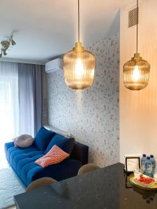 a living room with a blue couch and two lights at Apartament KARMEL in Przemyśl