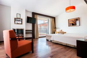 ein Schlafzimmer mit einem Bett, einem Stuhl und einem TV in der Unterkunft Hotel Isla de La Garena in Alcalá de Henares