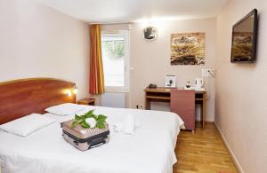 a hotel room with a bed with a table and a window at Logis Hotel Restaurant Bagatelle - 51530 Dizy in Épernay