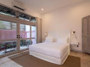 a bedroom with a white bed and a large window at Kresna By The Sea By Kresna Hospitality in Seminyak