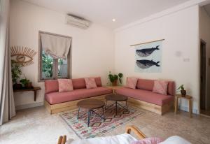 a living room with pink couches and a table at Kresna By The Sea By Kresna Hospitality in Seminyak