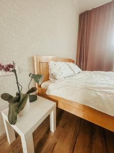 um quarto com uma cama e uma mesa com um vaso em Middle street apartment em Alūksne