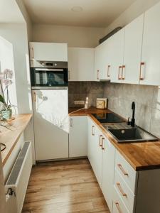 a kitchen with white cabinets and a sink and a refrigerator at Middle street apartment in Alūksne