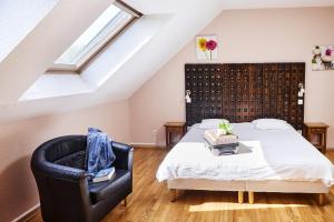 a bedroom with a bed and a black chair at Logis Hotel Restaurant Bagatelle - 51530 Dizy in Épernay +57 photos