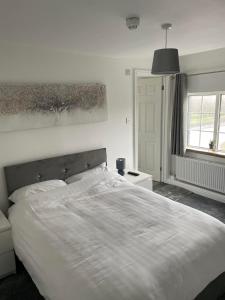 a bedroom with a large white bed and a window at OYO The Billingford Horseshoes in Scole