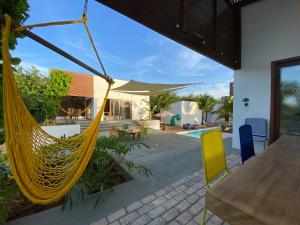 eine Terrasse mit einer Hängematte und einem Haus in der Unterkunft Maison dos Corais in São Miguel do Gostoso