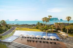 an aerial view of a pool with umbrellas and the ocean at The Grand Sumorum in Seogwipo
