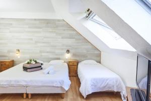 two beds in a attic bedroom with white walls at Logis Hotel Restaurant Bagatelle - 51530 Dizy in Épernay
