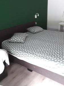 uma cama num quarto com uma parede verde em Le Jardin du Thé Bord de la Meuse em Namur