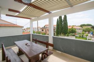 a wooden table and bench on a balcony with a view at Apartman V in Premantura near the center of town in Premantura