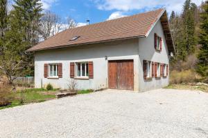 a small white house with a large garage at Gite Du Dombief in La Chaux-du-Dombief