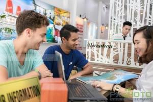 a group of people sitting at a table with a laptop at Hanoi Eastern Gate Hostel in Hanoi