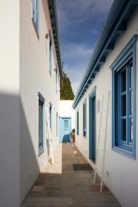 an alley between two white buildings with blue windows at Orloff Legacy Suites Hydra in Hydra