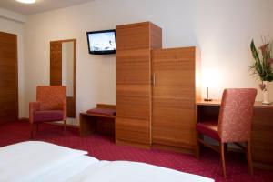 a hotel room with a bed and a cabinet with a television at Schillerhof Hotel GARNI in Vöcklabruck