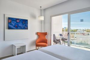 a bedroom with a bed and a chair and a window at Hotel Astoria Playa Adults Only 4* Sup in Port d'Alcudia