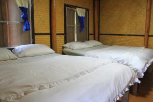 two beds with white sheets in a room at Rangbondoi - Birdhides Included and available for birding guide in Ban Phae