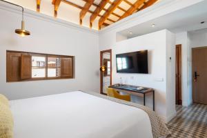 パルマ・デ・マヨルカにあるHotel Can Quetglasのベッド、机、テレビのある寝室