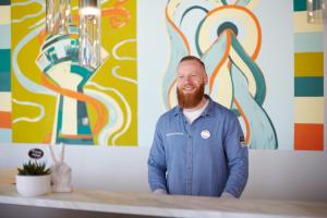 un homme avec une barbe debout devant un comptoir dans l'établissement the niu Hub, à Düsseldorf