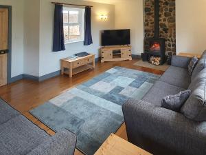 a living room with a couch and a tv and a fireplace at West End Farmhouse in Barmston