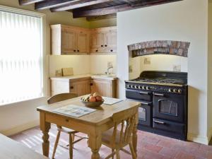 Barmston的住宿－West End Farmhouse，厨房配有木桌和炉灶。