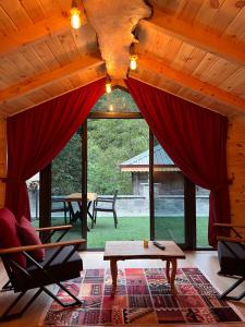 a living room with red curtains and a table and chairs at Esinti Bungalows Otel in Çamlıhemşin
