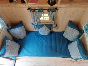 uma cama na parte de trás de uma caravana com almofadas azuis em La cabane de Merlin em Les Molières