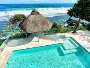 a swimming pool with a straw umbrella and the ocean at Domaine de la Falaise private villa in Souillac