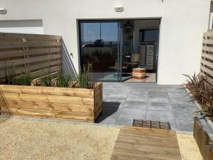 a patio with a wooden planter in front of a house at Studio neuf déco vintage face mer,terrasse ,jardin,wifi,parking in Saint-Hilaire-de-Riez