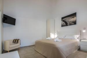 een witte slaapkamer met een bed en een stoel bij De' Villanova House in Brindisi
