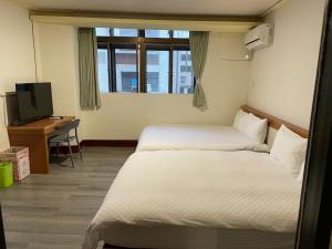 花蓮市的住宿－金桔民宿，客房设有两张床、一张桌子和一台电视。