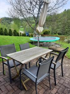ein Picknicktisch und Stühle mit einem Regenschirm, einem Tisch und einem Trampolin in der Unterkunft Ferienwohnung Bouma in Helminghausen