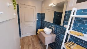 La salle de bains est pourvue de carrelage bleu, d'un lavabo et d'un miroir. dans l'établissement Ô de Vents - à 30m de la plage, à Sangatte