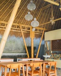 une salle à manger avec des tables et des chaises et un plafond en paille dans l'établissement Bambu Lokha Guest house, Gianyar Bali, à Ubud