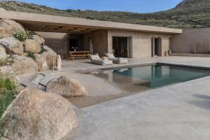 a house with a swimming pool and some rocks at Homa Serifos pool villas in Serifos Chora