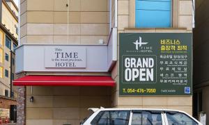 Gumi time hotel في كومي: سيارة متوقفة أمام لافتة كبيرة مفتوحة