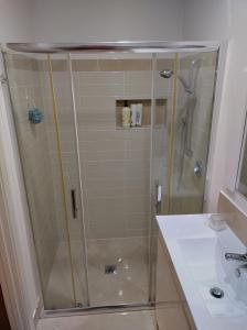 una ducha con una puerta de cristal junto a un lavabo en Macleay Island Getaway, en Macleay Island