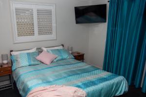 1 dormitorio con 1 cama con almohadas azules y rosas en Macleay Island Getaway, en Macleay Island