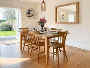 a dining room table with chairs and a mirror at Barn Cottage in Saint Mawgan