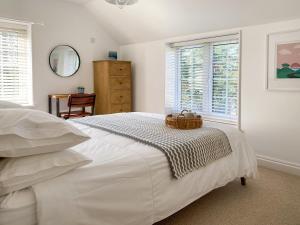 a white bedroom with a bed with a basket on it at Barn Cottage in Saint Mawgan