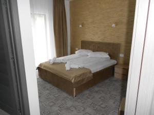 - une chambre avec un lit doté de draps et d'oreillers blancs dans l'établissement Andrana, à Căciulata