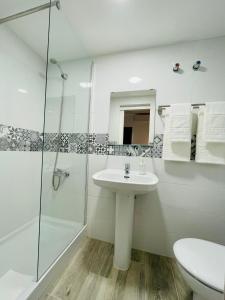 a white bathroom with a sink and a shower at Micaela Charming Hostal in Torremolinos